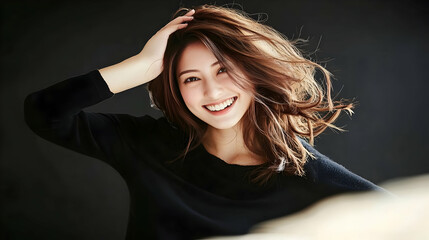Naklejka premium Smiling Woman Touches Hair, Wearing Black Shirt on Dark Background Gracefully