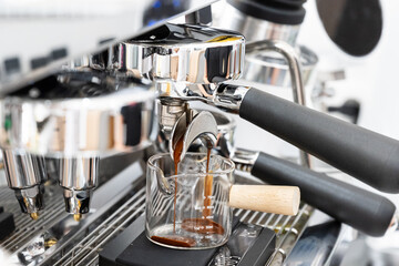 Coffee machine brewing espresso in to glass cup.Barista while preparing and working with coffee machine and making espresso coffee from arabica coffee beans.