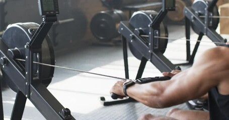 Using rowing machine, man exercising in gym, focusing on fitness and strength