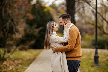 Naklejka premium Side view of happy couple in love hugging and cuddling in city park.