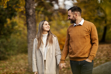 Obraz premium Portrait of affectionate young couple holding hands and taking a walk in city park.