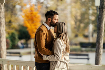 Loving couple kissing and hugging in public park.