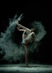 Dynamic dancer creating art with flour in a dark studio