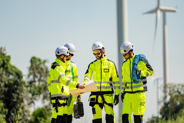 Fototapeta premium Team of workers reviewing plans at a wind farm on a clear day