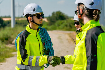 Fototapeta premium Team of workers in bright safety gear shake hands on an outdoor site during a sunny day
