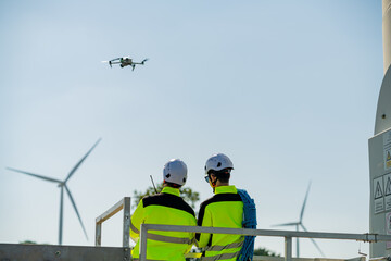 Technicians operating a drone for wind turbine inspection at a renewable energy site during daylight