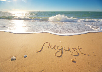August word written on sea sand shore beach at day.