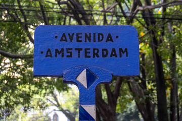 A bright blue art deco street sign with the name of Avenida Amsterdam (Amsterdam Avenue) in the trendy La Condesa neighborhood in Cuauhtemoc borough of Mexico City, Mexico