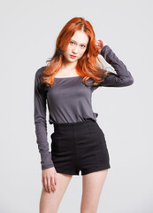 Fototapeta premium Half-body fashion beauty portrait of asian beautiful sexy cheerful confident young woman with long orange or red hair, model wearing long-sleeved shirt, black shorts posing looking on white background