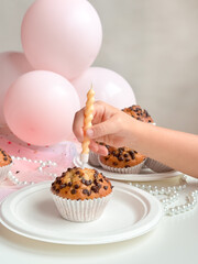 Childs birthday celebration with cupcake, candle, and pink balloons. Birthday concept