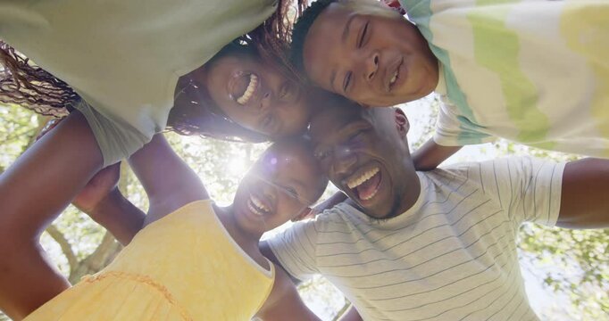 Smiling family of four huddling together outdoors, enjoying time together