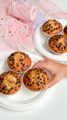 Child reaching for chocolate chip muffins on decorative table setting. Birthday concept
