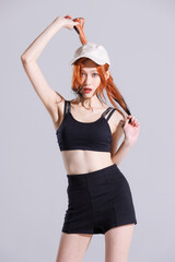Fashion portrait of asian beautiful sexy attractive cheerful confident young woman with long orange hair model wearing fashionable black outfit and cap standing looking camera pose on white background