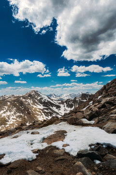 Rocky Mountain top with fluffy clouds and blue sky