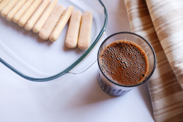Black coffee with foam in a glass and Savoyard cookies for tiramisu