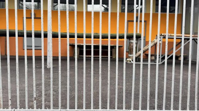 A tiger is in a cage with a fence. The cage is in a zoo
