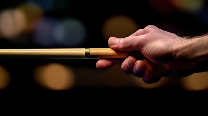 A close-up of a hand gripping a cue stick, aiming for the shot, with a blurred background of the billiard table