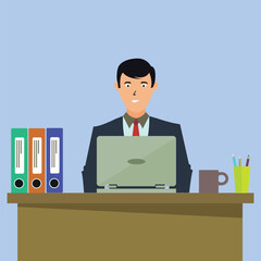 A man in a suit working on his laptop at his office desk with office supplies