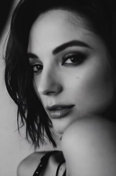 Brunette female model, cosmetic make-up shoot, portrait video. Slow motion, slowing gazing towards camera. Smokey make-up, red lipstick. Dramatic. Elegant.	