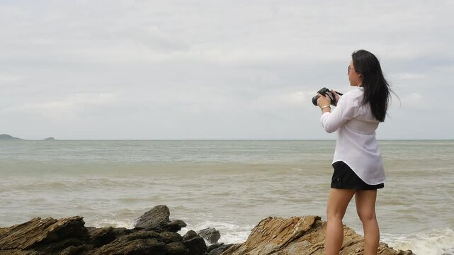 A Woman Standing on Rocks Gazing at the Calm Ocean Under a Cloudy Sky, Capturing a Sense of Peace, Reflection, and Connection with Nature&rsquo;s Boundless Beauty