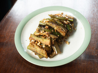 dish of grilled long eggplant with garlic on wooden table