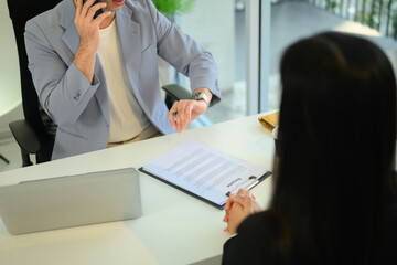 Recruiter speaking on the phone while reviewing a candidate resume during a job interview