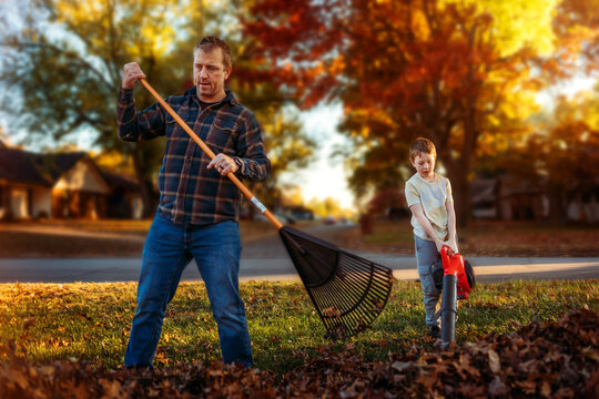 Father son raking leaves in colorful autumn background