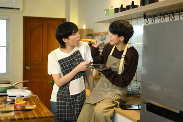Young male gay couple preparing breakfast at counter in warm kitchen