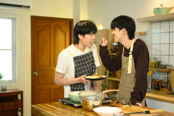 Loving male gay couple preparing a delicious breakfast at counter in warm kitchen