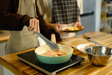 Young male gay couple preparing breakfast at counter in warm kitchen