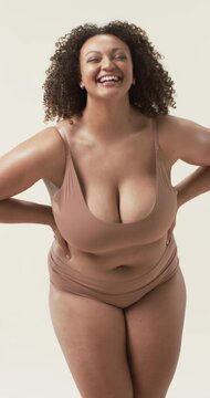 Vertical video: Smiling plus size woman in underwear posing confidently, embracing body positivity