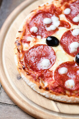 Pizza with salami and mozzarella cheese. Wooden background. Soft focus. Close up.	