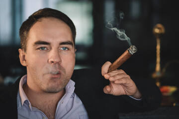 man smokes a cigar and the smoke released from the mouth