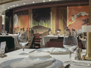 Art Deco interior design style furniture, carpets and paneling onboard modern ocean liner cruiseship cruise ship main dining room restaurant with flower deco and set tables