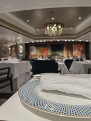 Art Deco interior design style furniture, carpets and paneling onboard modern ocean liner cruiseship cruise ship main dining room restaurant with flower deco and set tables