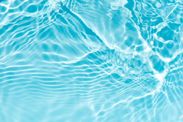 Blue water with ripples on the surface. Defocus blurred transparent blue colored clear calm water surface texture with splashes and bubbles. Water waves with shining pattern texture background.