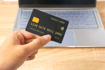 Pov first person holding black mockup credit card for online shop on laptop in home