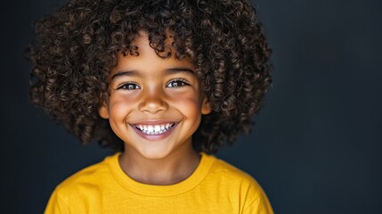 A little boy with curly hair smiles at the camera