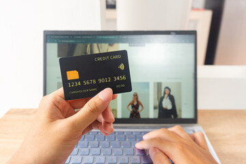 Pov first person holding black mockup credit card while typing for online shop on laptop in home