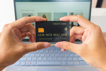 Pov first person holding black mockup credit card with two hands for online shop on laptop in home