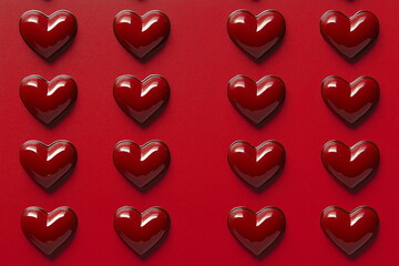 Valentine's Day heart background. A neat arrangement of glossy, red, heart-shaped chocolates placed on a bold red background, symbolizing sweetness and love, ideal for Valentine's Day advertisements.