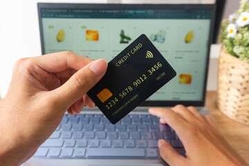 Pov first person holding black mockup credit card while typing for online shop on laptop in home