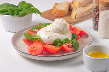 Delicious Italian caprese salad with sliced mozzarella, tomatoes, basil, and bread on background. 