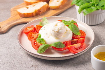 Delicious Italian caprese salad with sliced mozzarella, tomatoes, basil, and bread on background. 
