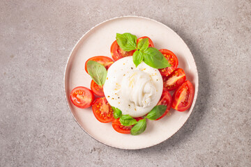 Delicious Italian caprese salad with sliced mozzarella, tomatoes, basil, and bread on background. 