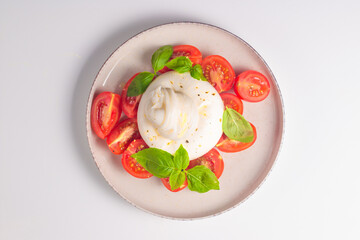 Delicious Italian caprese salad with sliced mozzarella, tomatoes, basil, and bread on background. 