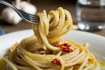 A fork lifts a delicious strand of spaghetti aglio e olio, seasoned with garlic, chili flakes, and olive oil.