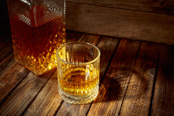 Elegant whiskey glass and decanter on a old wooden table.