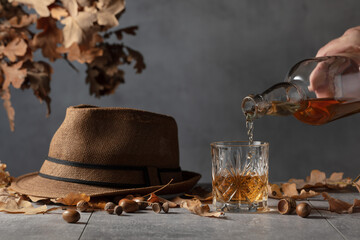 Whiskey on a grey stone table with dried-up oak leaves.