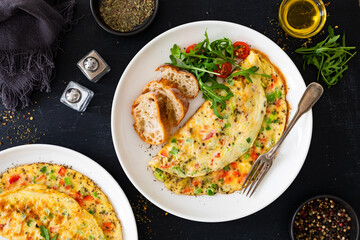 Omelette - scrambled eggs with red and green bell pepper on black table	